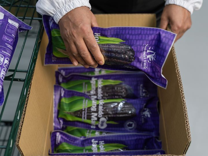 Hands placing a finished Natural Fare pack into a carton
